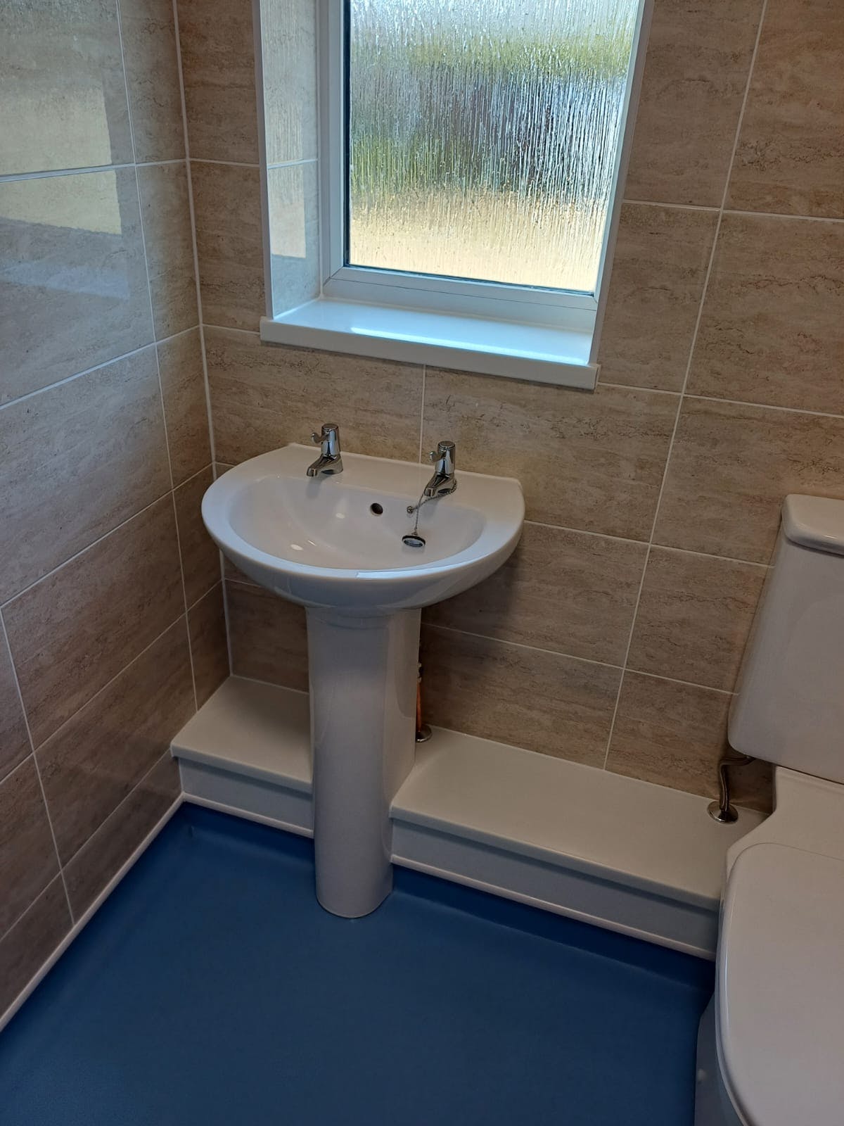 Accessible bathroom with pedestal basin and raised-height WC in a mobility wet room adaptation in Batley