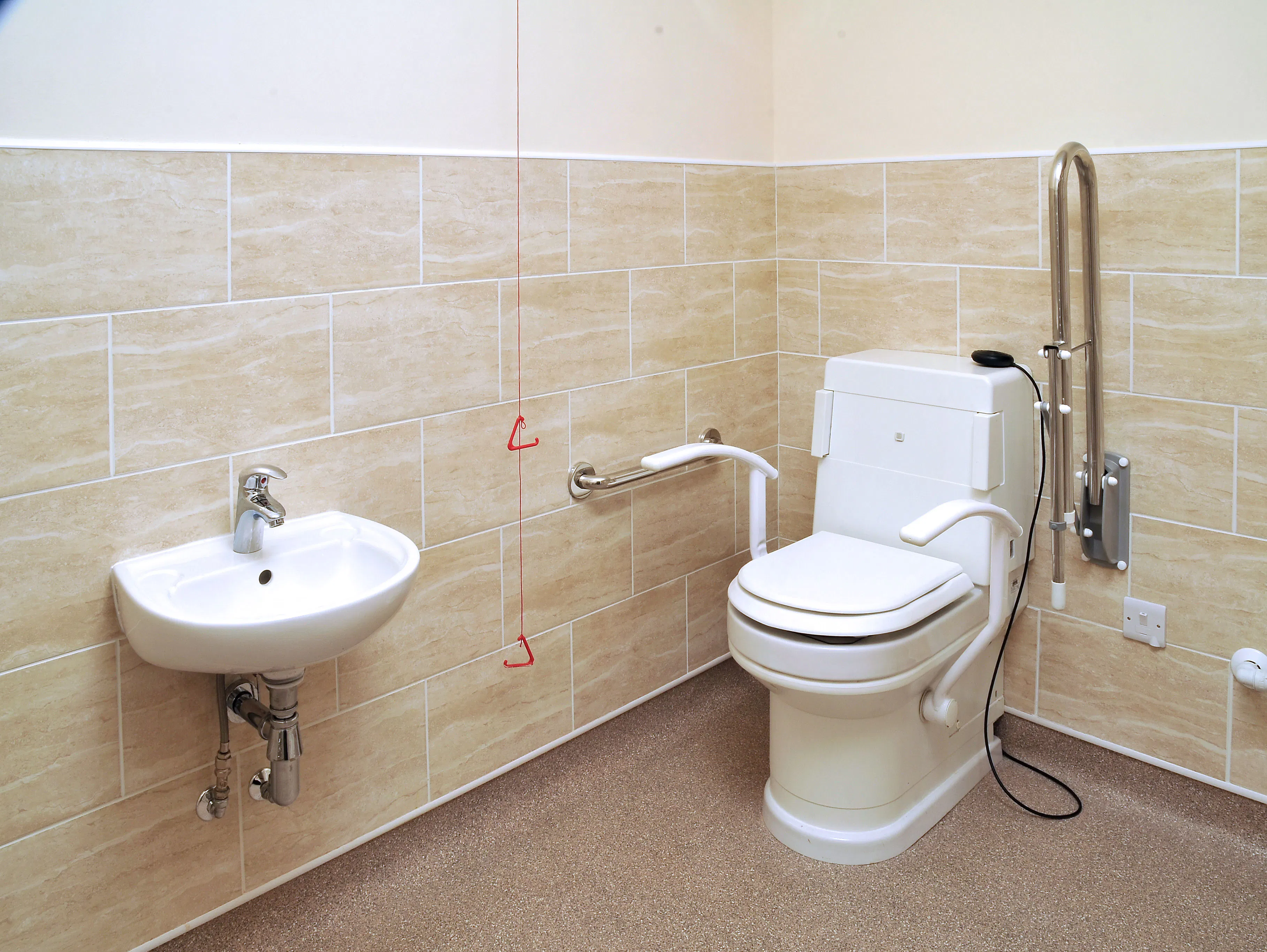 Disabled bathroom showroom display in Leeds featuring a wash and dry toilet, grab rails and compact wall-mounted disabled basin