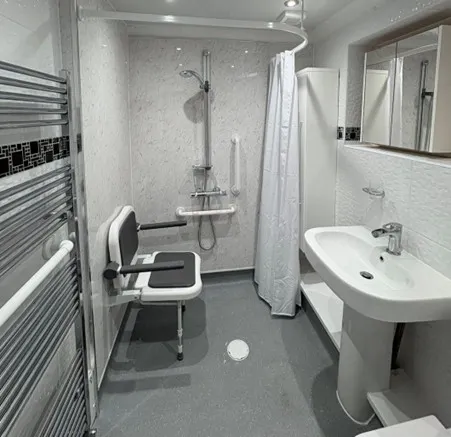 Small disabled wet room layout with wall-mounted shower seat and slip-resistant flooring