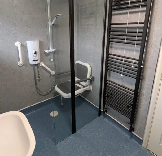 Modern mobility bathroom with accessible shower, support rails, and non-slip flooring