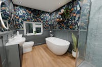 Luxury bathroom with freestanding bath and botanical wallpaper.