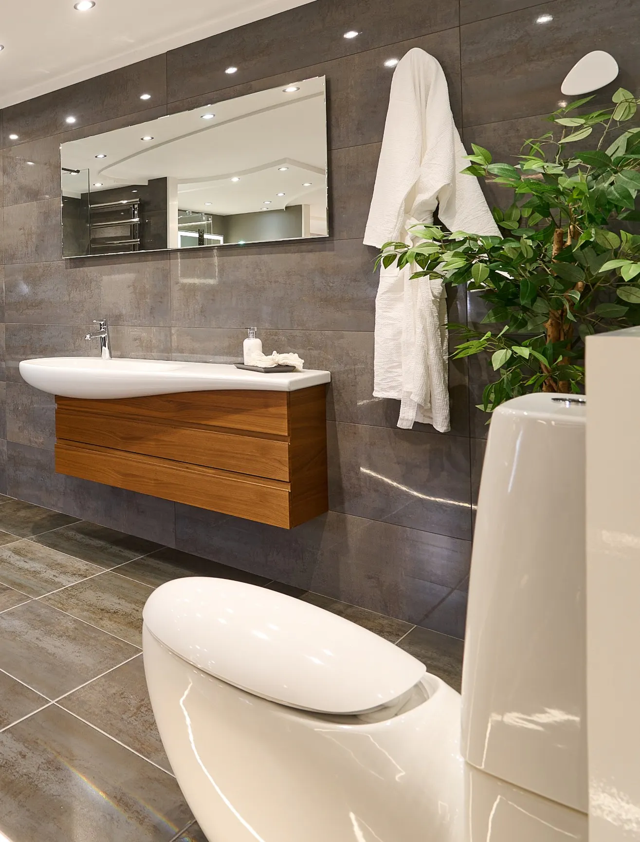 Elongated Oval Modern Toilet in a Contemporary Bathroom with Floating Walnut Vanity Unit.