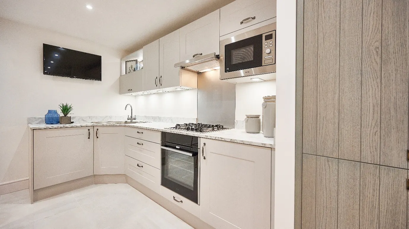 Small L shaped kitchen layout with light cabinetry and integrated oven