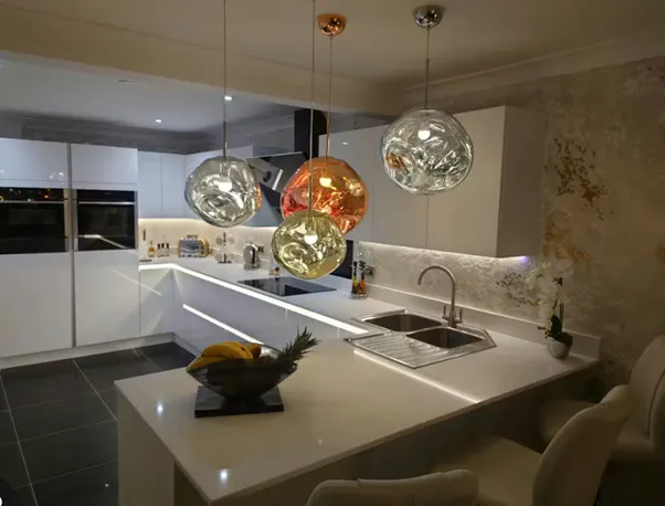 Modern white L shaped kitchen with peninsula and statement pendant lighting